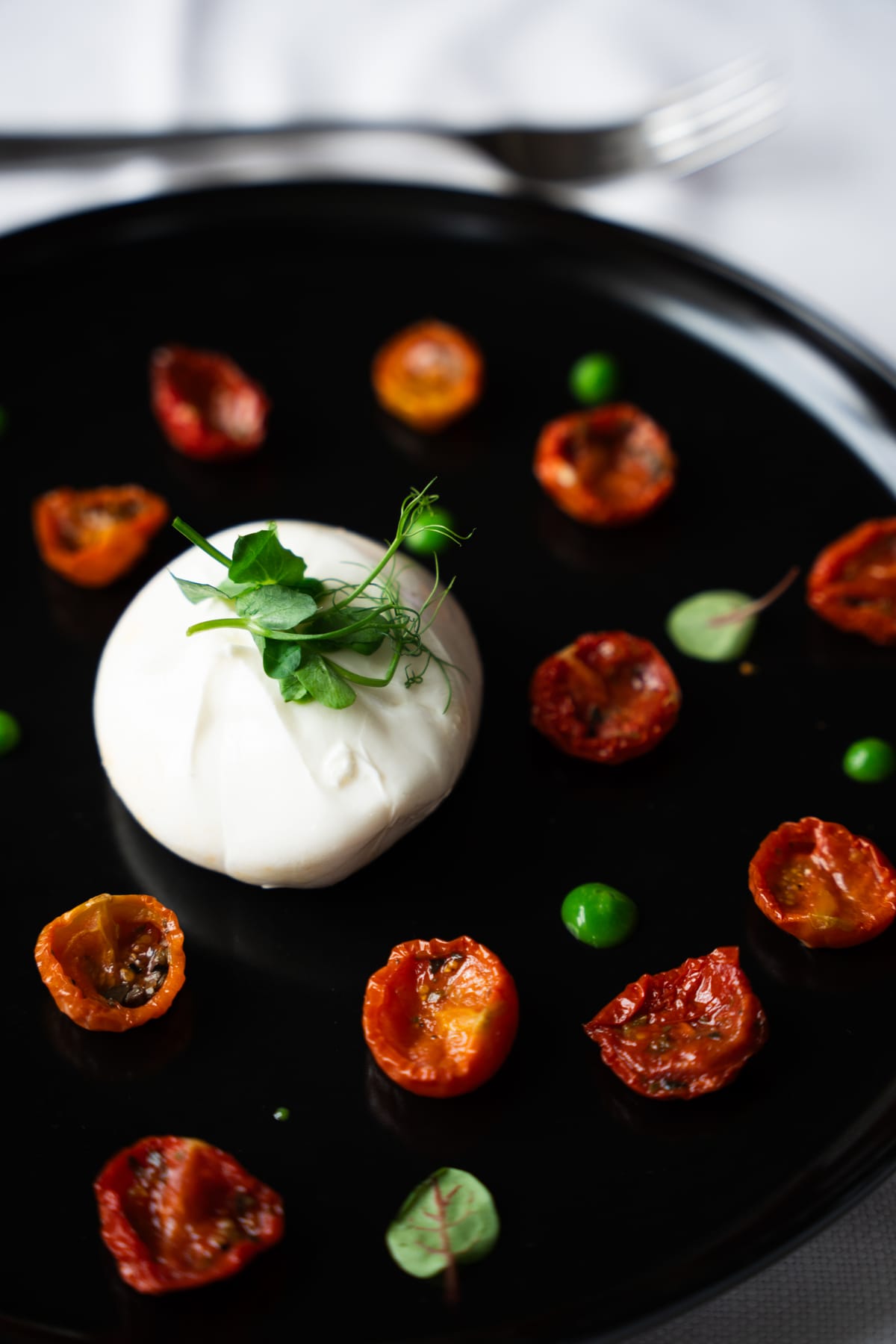 Burrata con pomodorini confit su piatto nero