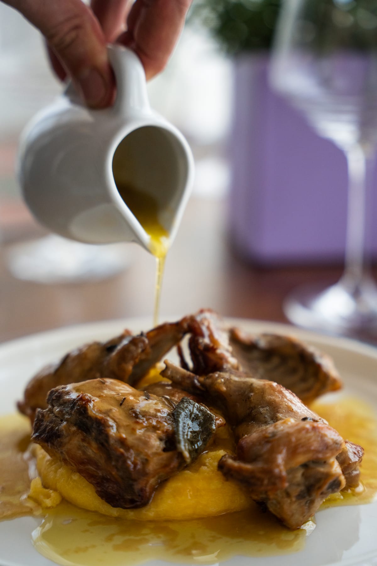Coniglio alla bresciana con polenta, mentre si versa il fondo di cottura